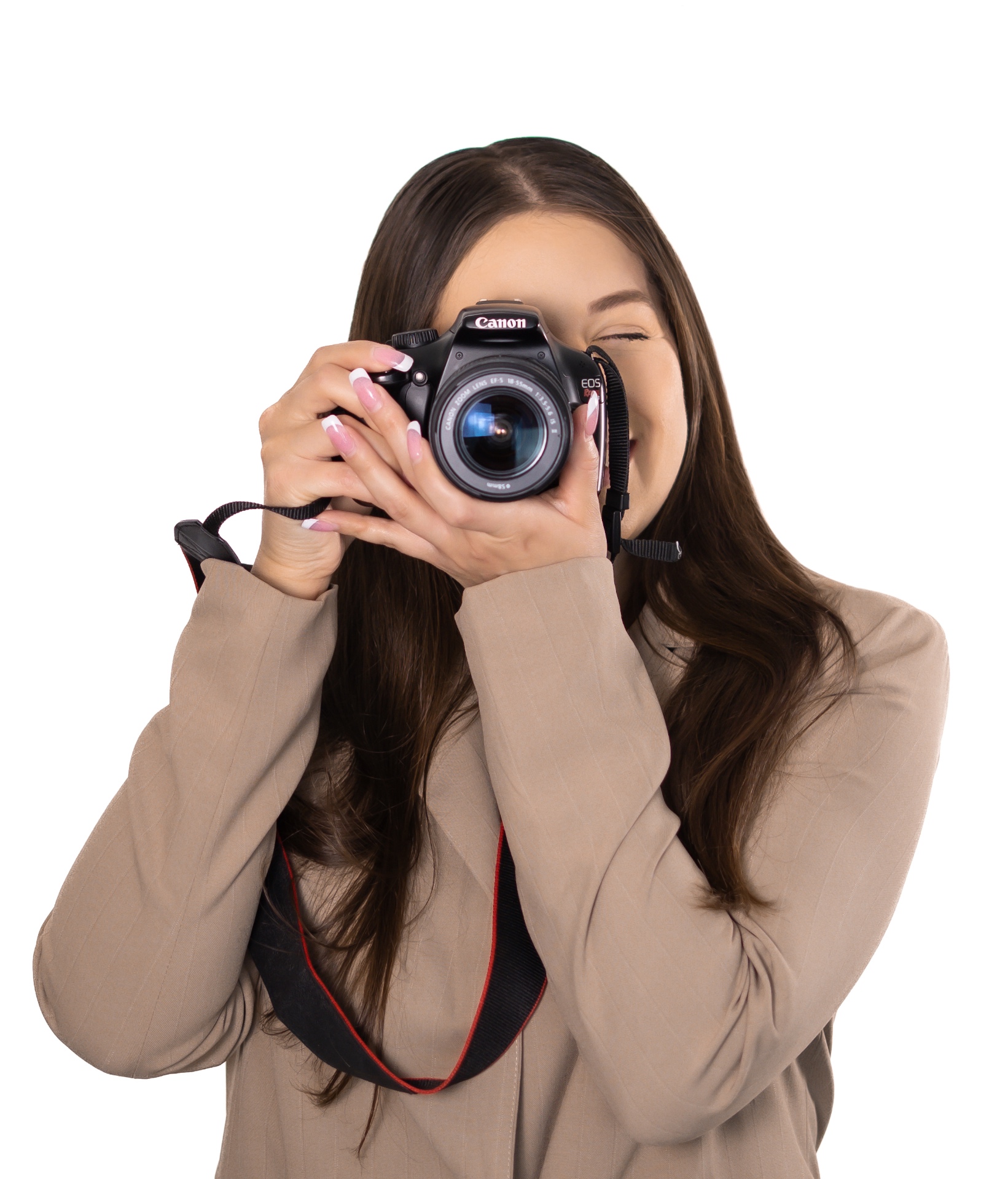 Adriana Rose Murillo in a tan blazer raising a camera to her eye against a white studio background.